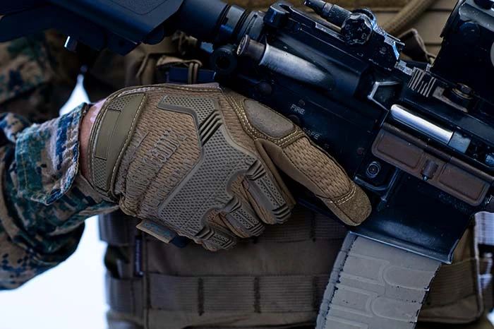 a person wearing tactical gloves holds an airosft gun