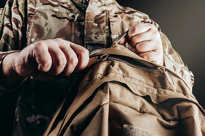 una persona vestida de uniforme sostiene una mochila militar