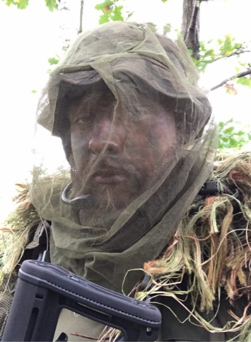 an airsoft player in face camouflage and camouflage uniform