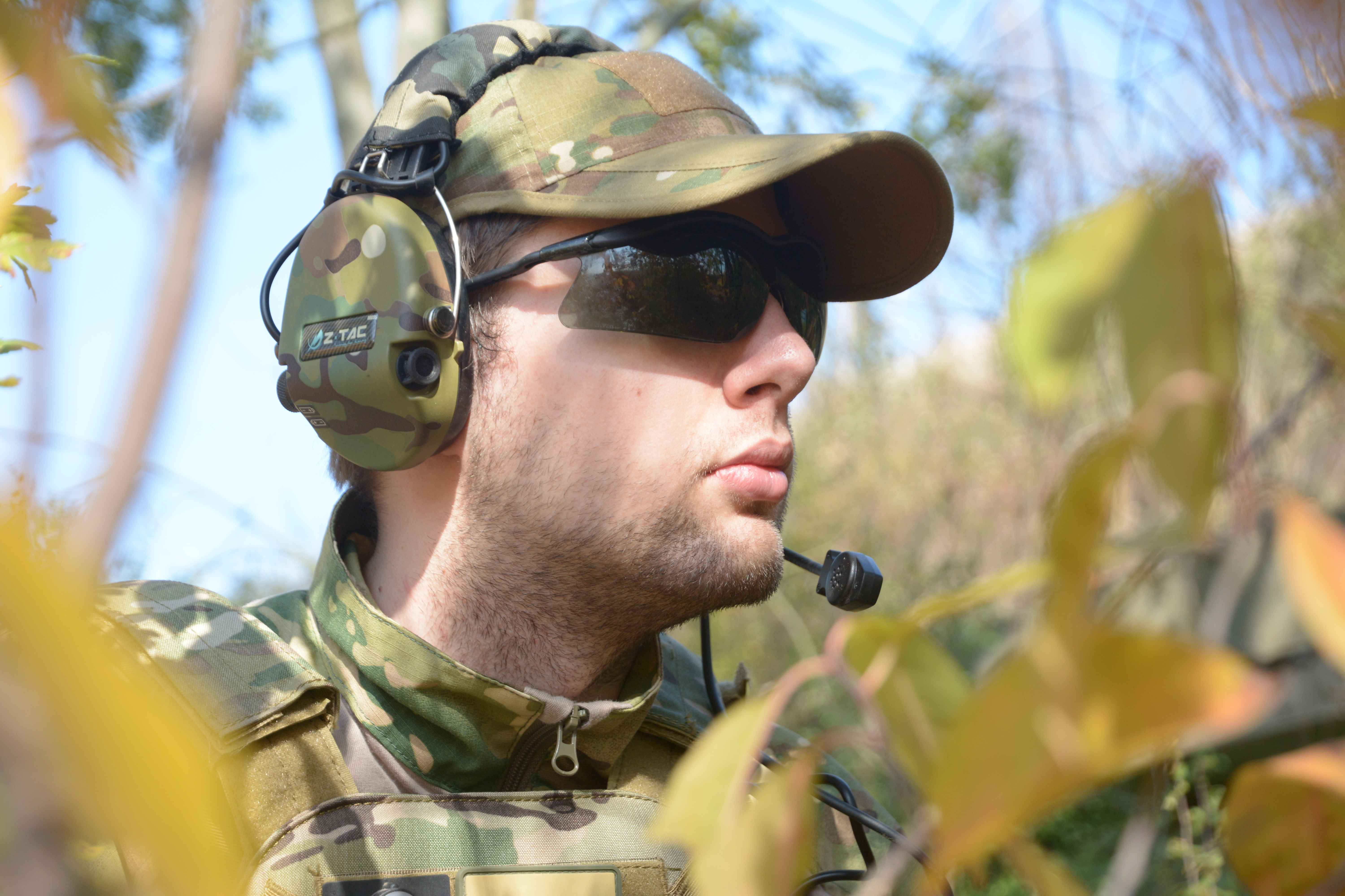 mężczyzna w czapce taktyccznje, ciemnych okularach i zestawie słuchawkowym