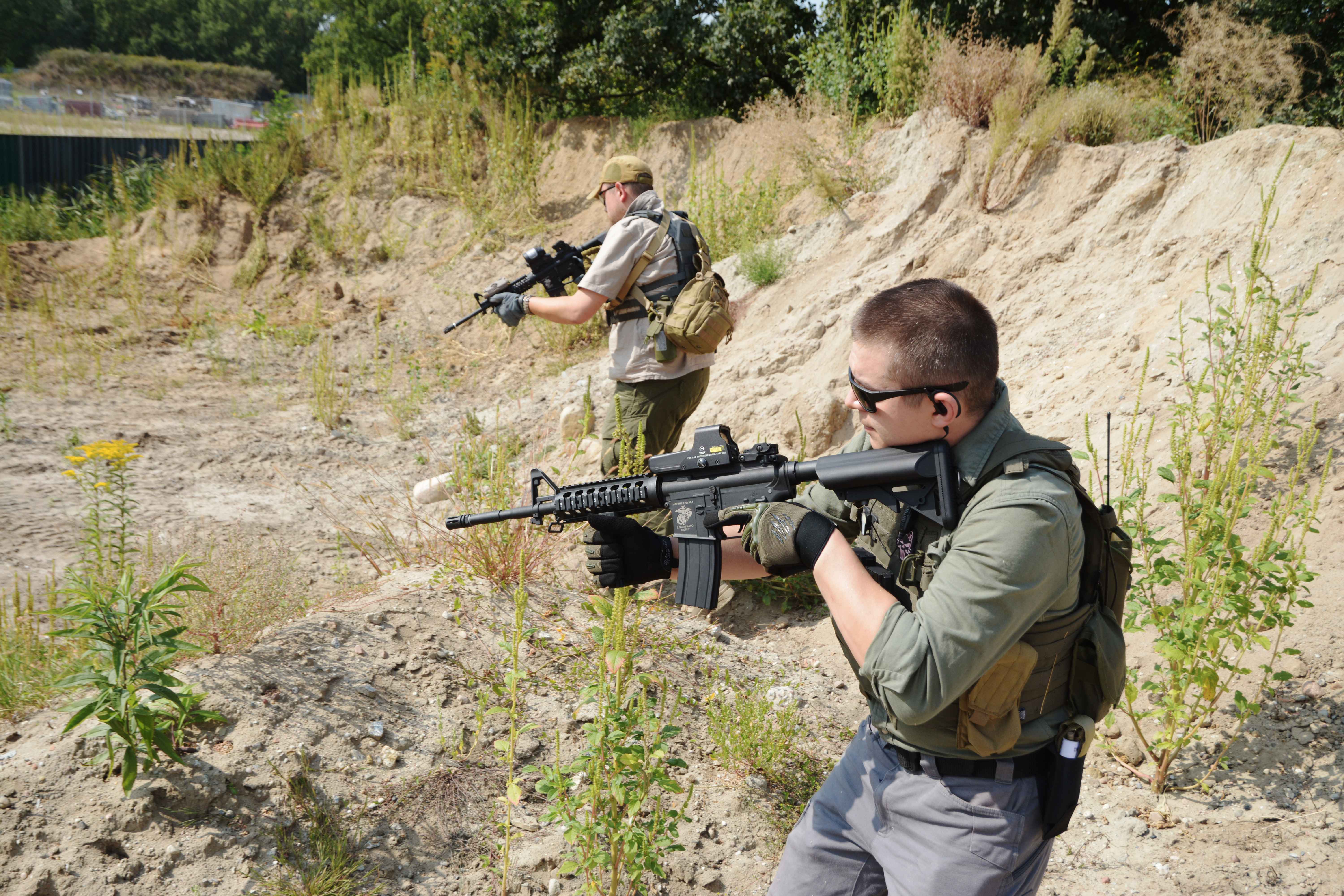 mężczyźni w odzieży militarnej z replikami asg, idą mierząc z replik, odzież taktyczna, okulary ochronne