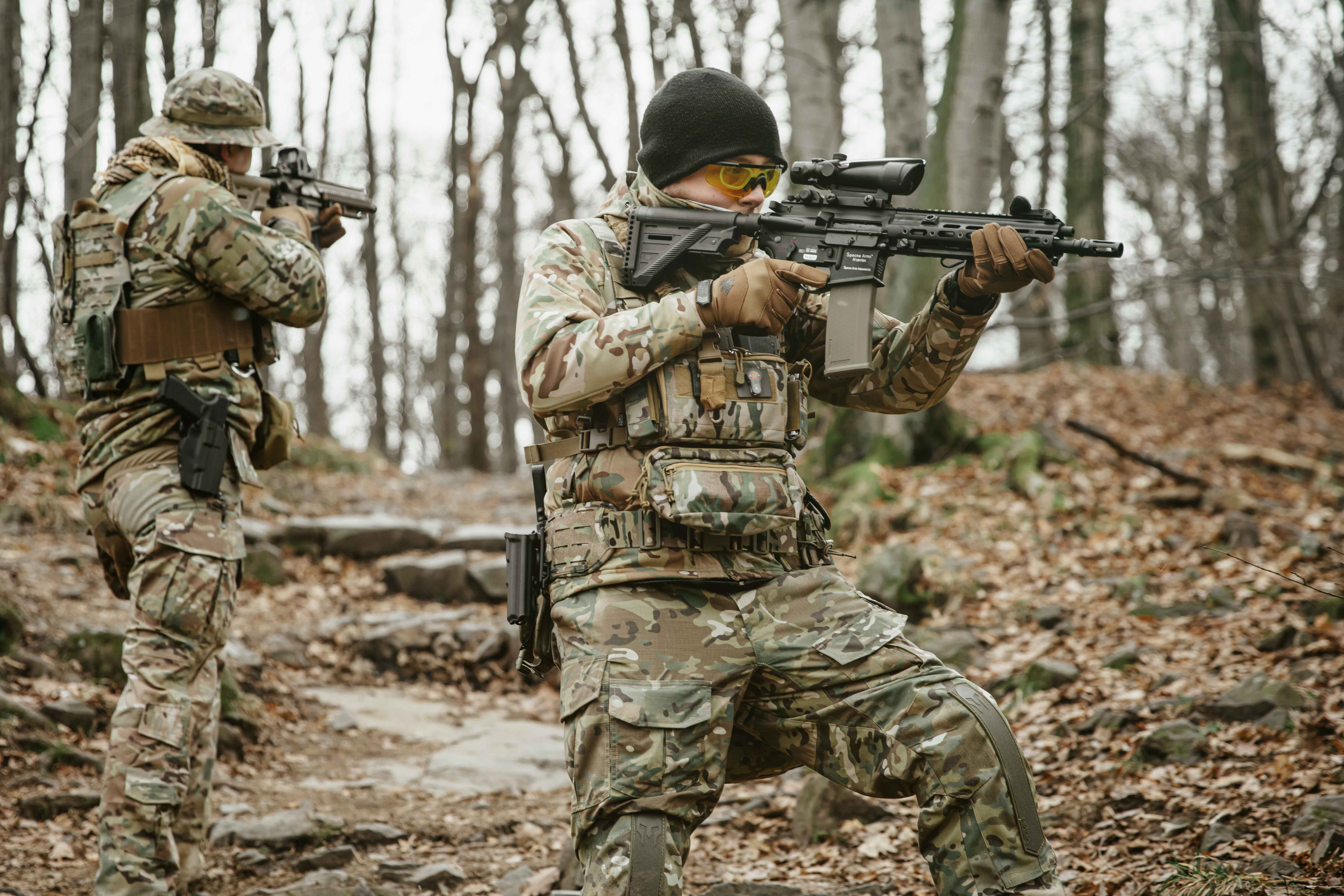 dwóch strzelców w mundurach, okularach ochronnych i nakryciach głowy; dwie repliki airsoft