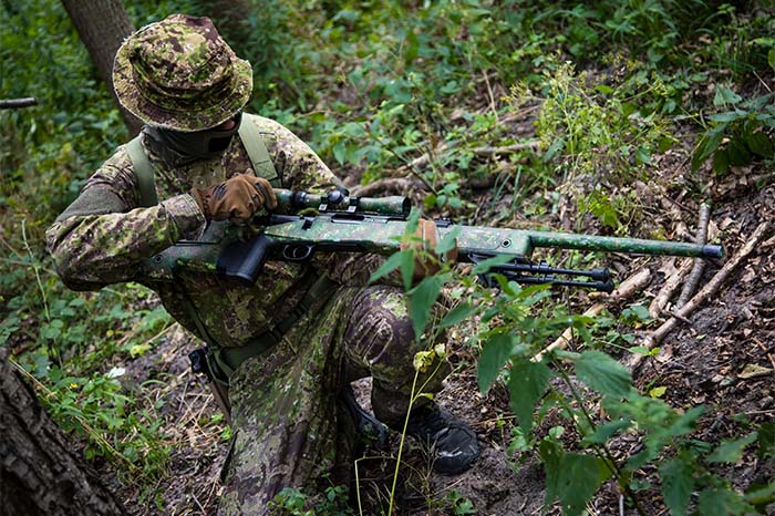 sniper in the forest holding an airsoft gun 
