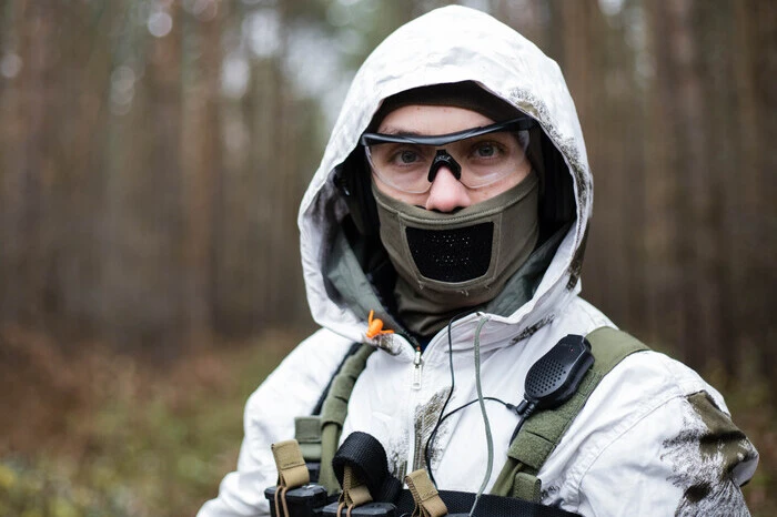airsoftový hráč střílí v lese v zimních maskáčích